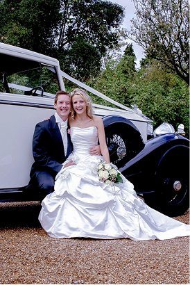 Bride and groom by a vintage wedding car